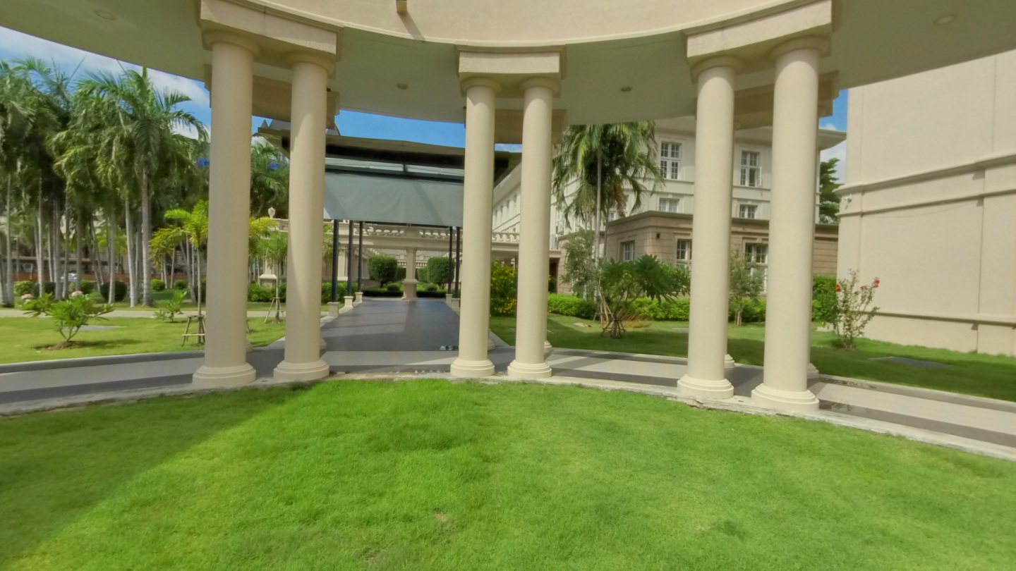 School courtyard with cream columns, covered walkways, palms and a green lawn