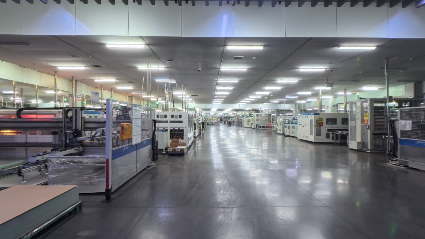 Solar panel production equipment along a brightly lit factory aisle